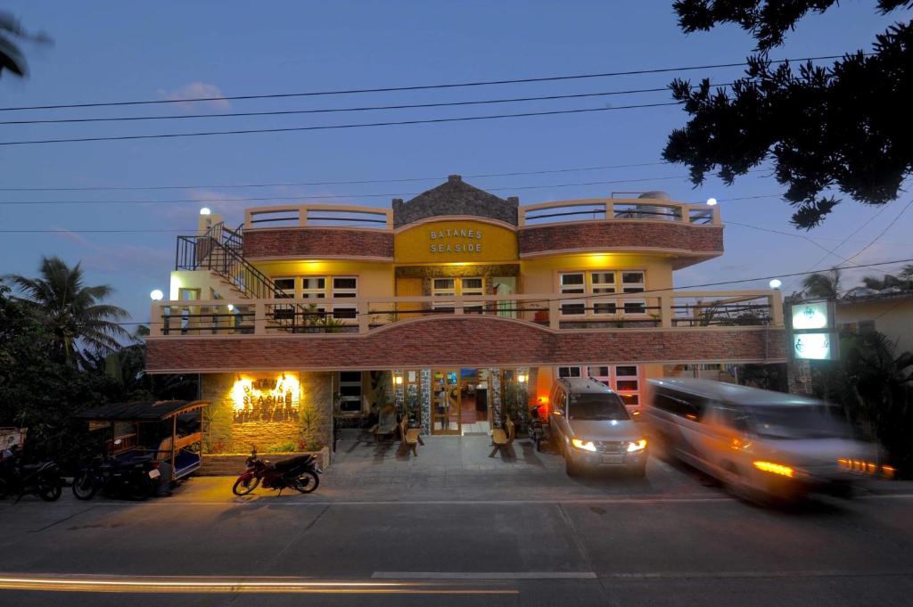 a building on a street with cars driving past it at Batanes Seaside Lodge & Restaurant in Basco