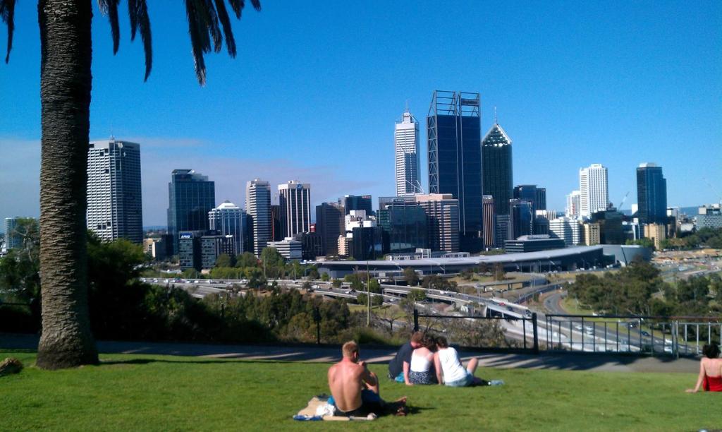 personas sentadas en el césped en un parque con vistas a una ciudad en The Hive Hostel - Traveler Friendly, Passport Only, en Perth