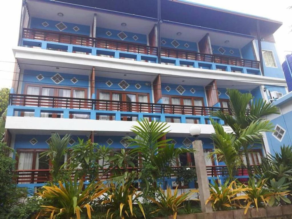 um edifício azul com palmeiras em frente em Mint Guesthouse em Ko Tao