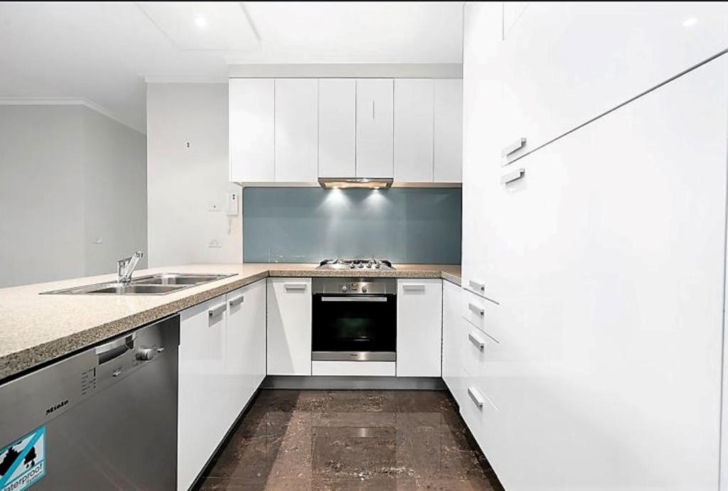 een witte keuken met een wastafel en een fornuis bij ReadySet Apartments at Southbank One in Melbourne