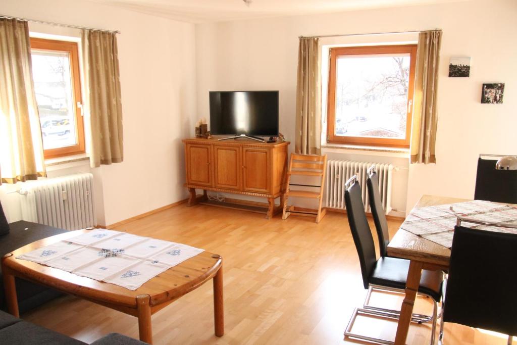 Una sala de estar con un televisor y una mesa y sillas. en Alpen - Apartments II, en Garmisch-Partenkirchen