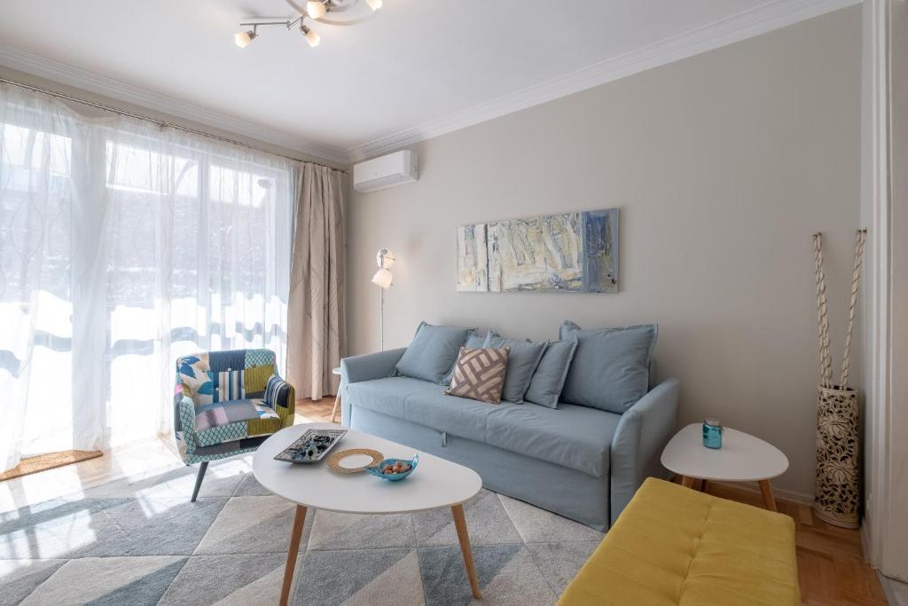 een woonkamer met een blauwe bank en 2 tafels bij Two Bedroom Apartment Near to Doctors Garden in Sofia