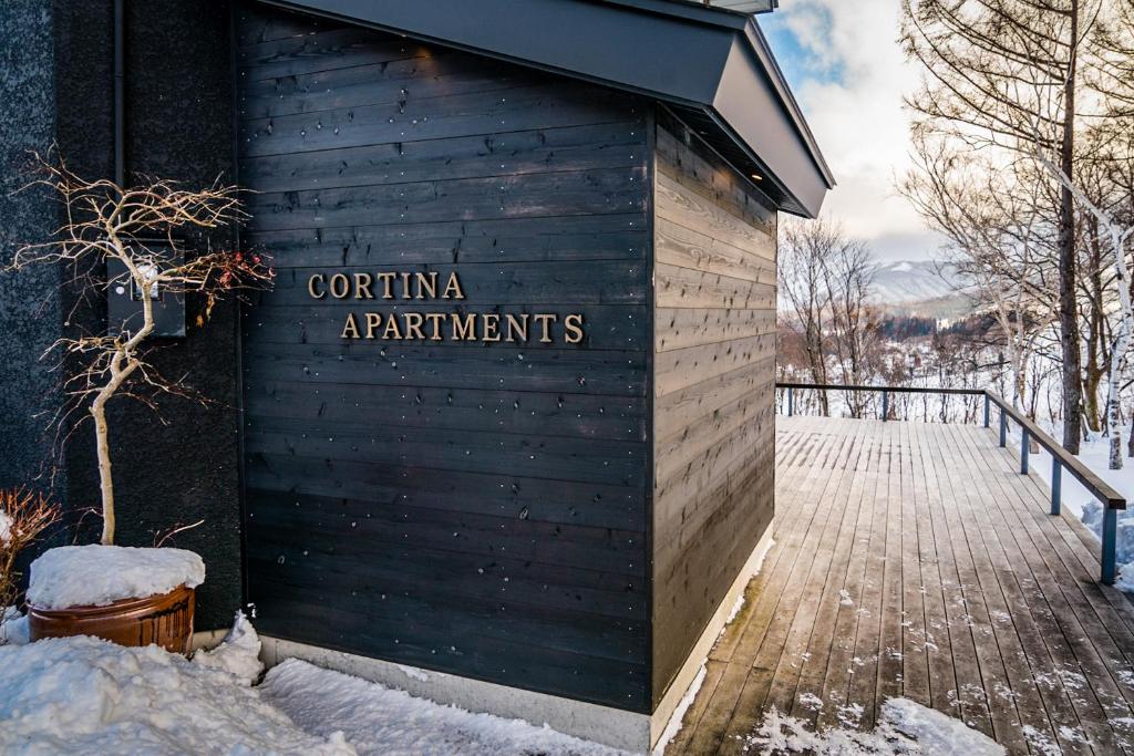 een bord aan de zijkant van een gebouw in de sneeuw bij Cortina Apartment in Otari