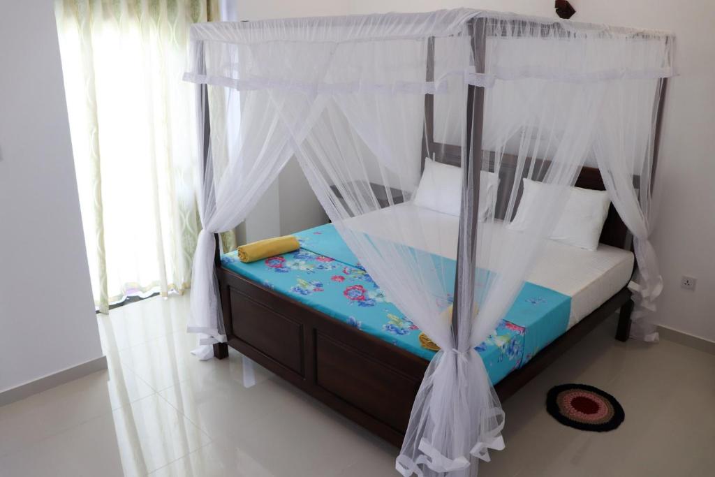 Schlafzimmer mit Himmelbett und weißen Vorhängen in der Unterkunft Sakura Calm Rest in Mirissa