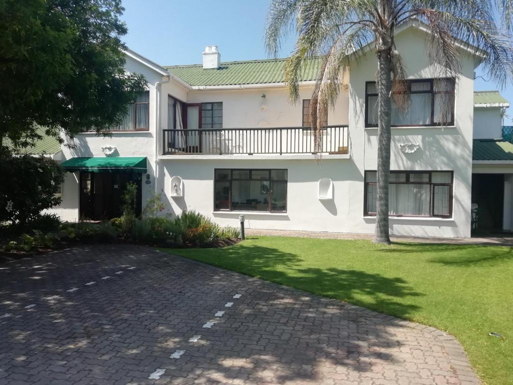 a large white house with a palm tree and a driveway at Point Lodge Knysna in Knysna