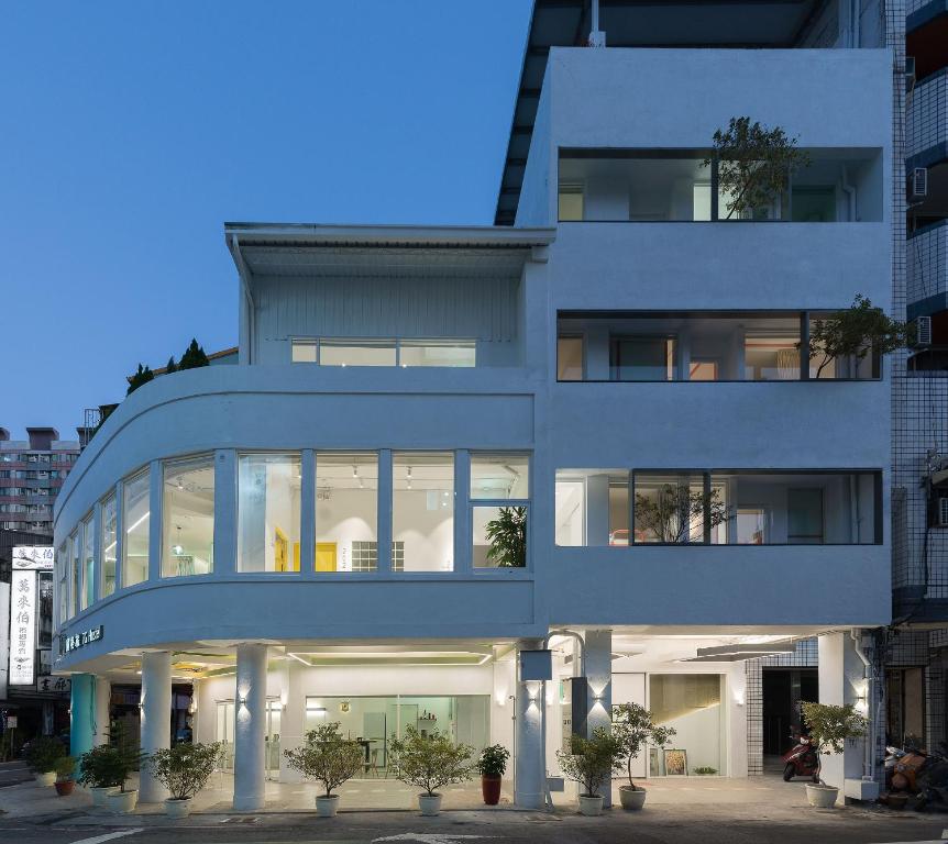 um edifício branco com grandes janelas e vasos de plantas em TG Hostel - stay together em Taichung