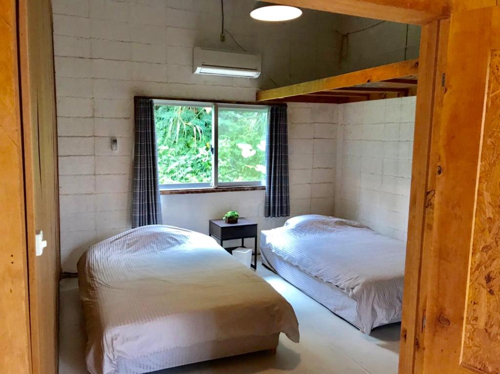 1 dormitorio con 2 camas y ventana en BRIDGE Iriomote Island, en Iriomote