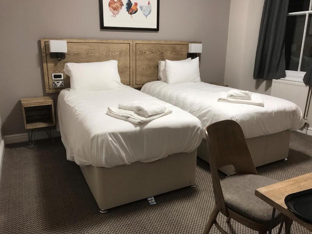two beds in a hotel room with towels on them at Markets Tavern Hotel in Brecon