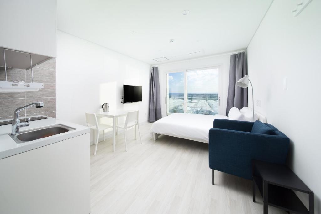ein Hotelzimmer mit einem Bett und einem Waschbecken sowie einer Küche in der Unterkunft Jeju Soo Pension in Seogwipo