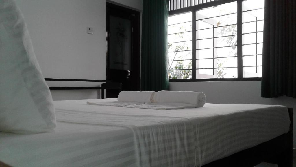 a bed with two towels on it with a window at Water Front Home Stay in Anuradhapura
