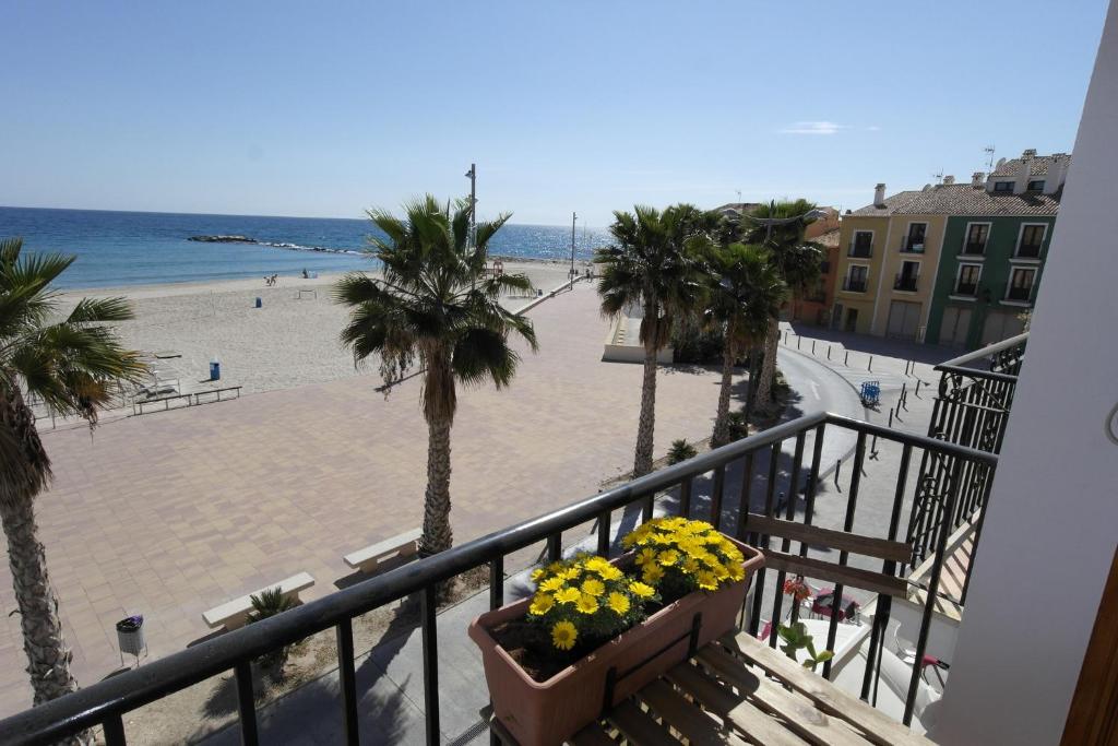a balcony with a view of a beach and palm trees at AR2B, coqueto apartamento en primera línea de playa in Villajoyosa