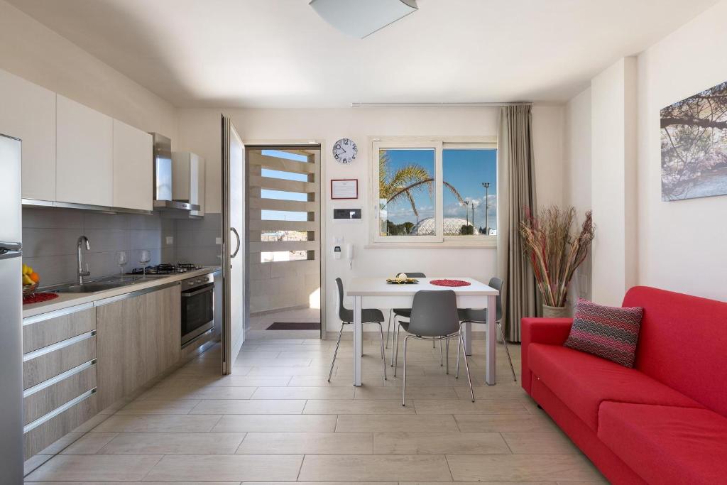 een keuken en een woonkamer met een rode bank en een tafel bij Le Dimore di Otranto in Otranto