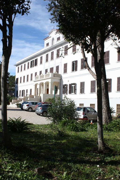 a large white building with cars parked in front of it at Ostello Villa Monte Mario in Rome
