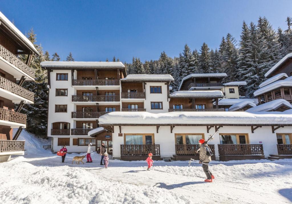 un grupo de personas en la nieve frente a un edificio en Résidence Odalys Le Front de Neige en Les Carroz d'Araches