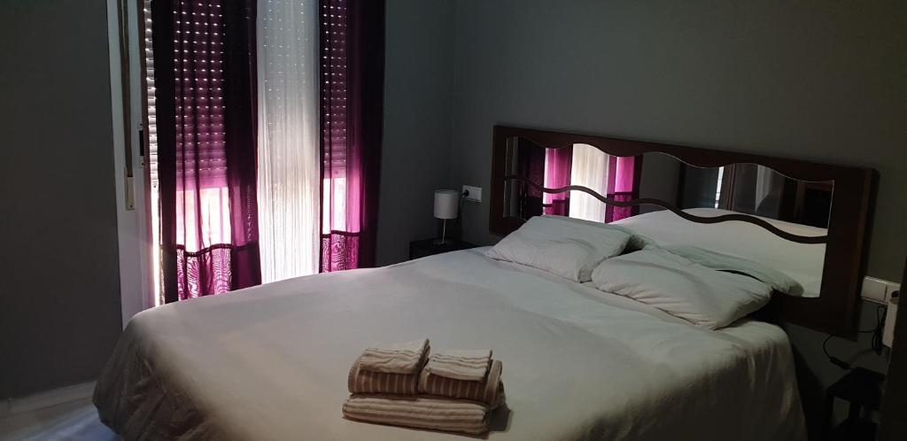 マラガにあるApartamento Omar Playaのベッドルーム(ピンクのカーテン付きの大きな白いベッド1台付)