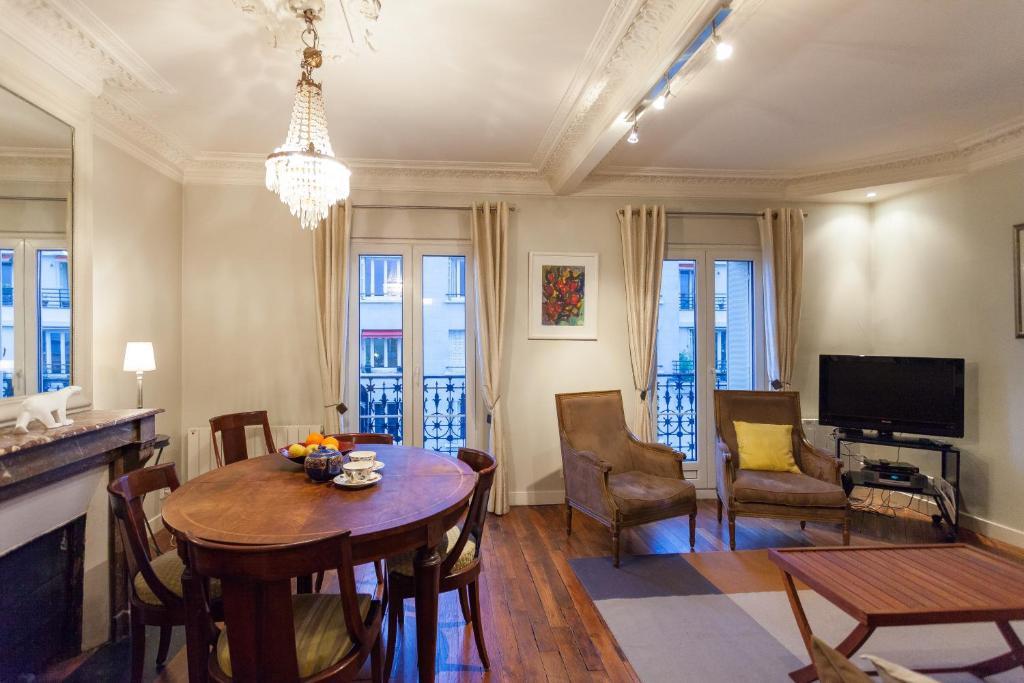 een woonkamer met een tafel en stoelen en een televisie bij Greeter-Appartement Haussmannien avec balcon in Parijs