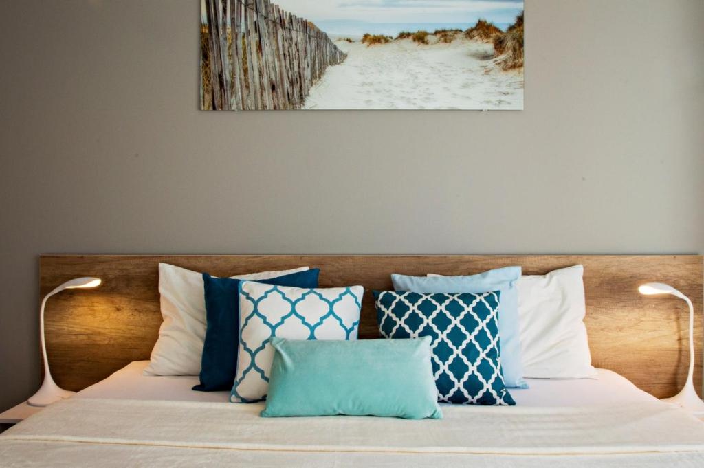 ein Bett mit blauen und weißen Kissen darauf in der Unterkunft Grand Apartments - Neptun Park Smile&Relax in Danzig