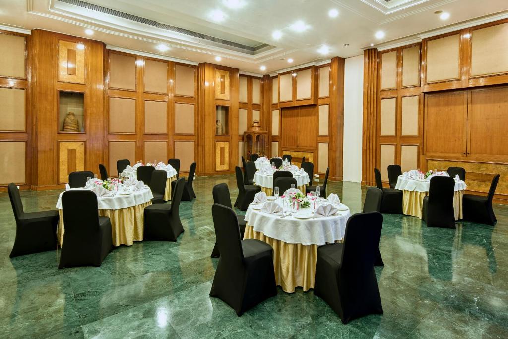 a banquet hall with tables and chairs and a podium at The Ummed Ahmedabad Airport in Ahmedabad
