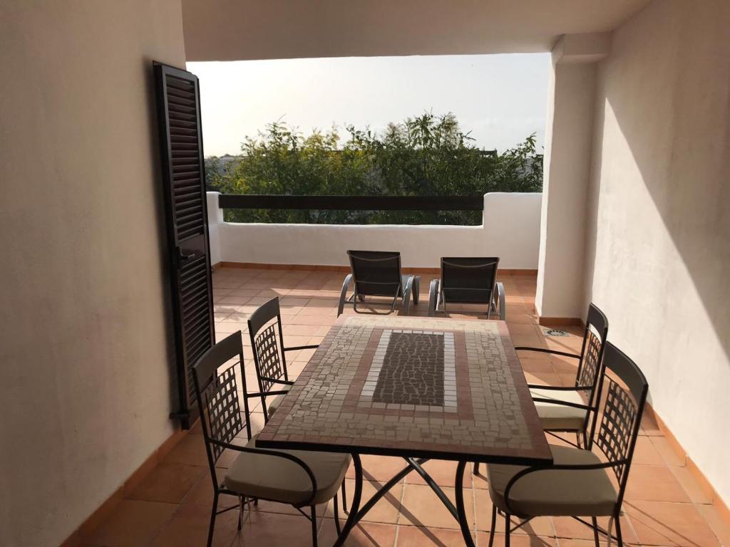 patio con mesa y sillas en el balcón en Luxury apartment set in Doña Julia Golf Course, en Casares