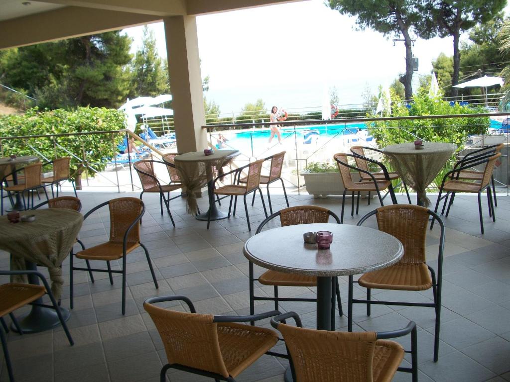a patio with tables and chairs and a swimming pool at Thea Hotel in Possidi