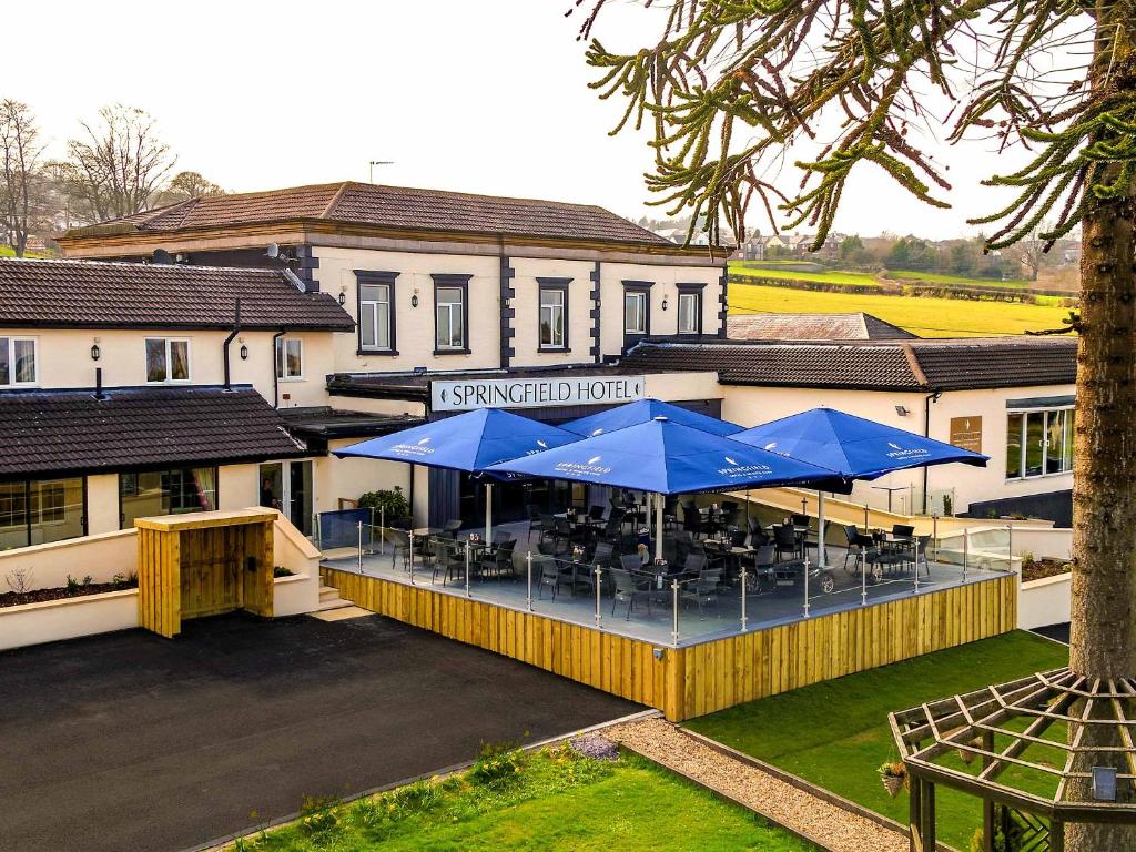 um restaurante com guarda-sóis azuis em frente a um edifício em Springfield Hotel & Health Club em Halkyn