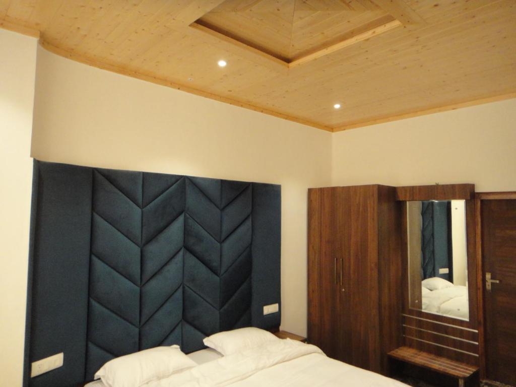 a bedroom with a black padded headboard and a mirror at The Hill Crest Inn in Shimla