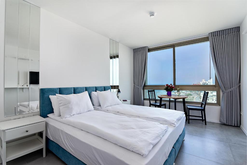 a bedroom with a large bed and a table with chairs at Netanya SeaView ApartHotel in Netanya