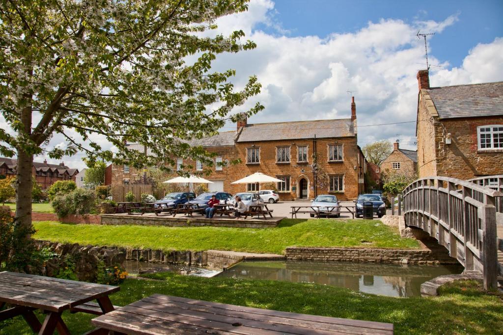 a bridge over a river in front of a building at Nevill Arms Inn in Medbourne