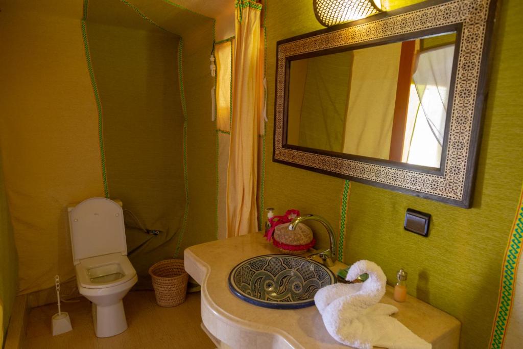 a bathroom with a sink and a toilet and a mirror at Sahara Desert Luxury Camp in Merzouga