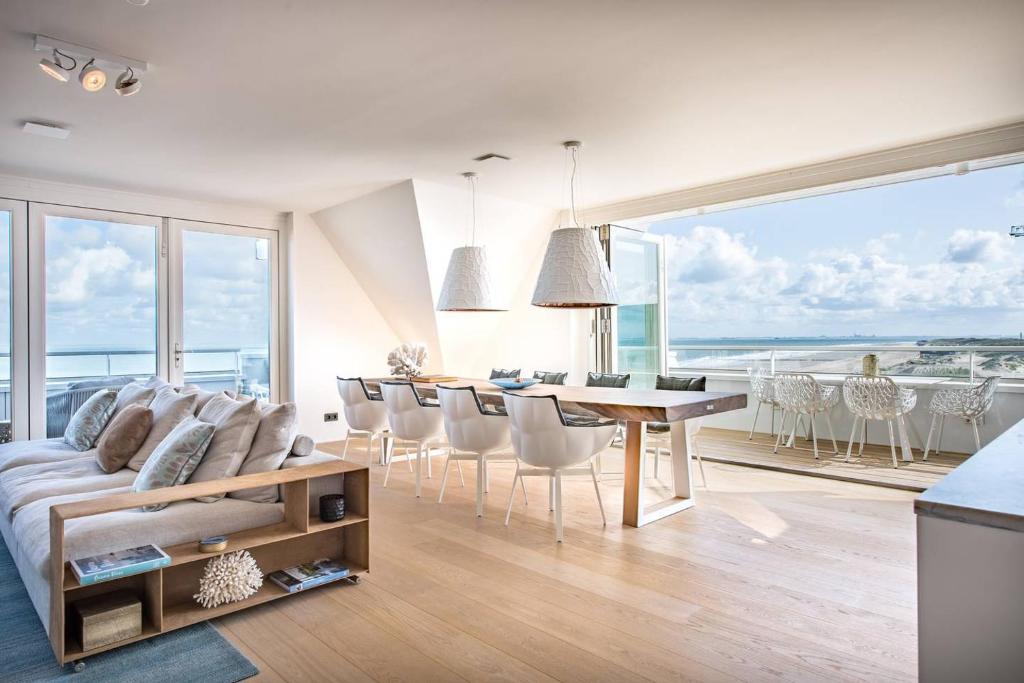 uma sala de estar com um sofá, uma mesa e cadeiras em Luxe apmt Zwembad Sauna op Duin aan Strand, registratie 17146E3088BEB97A4E16 em Cadzand-Bad