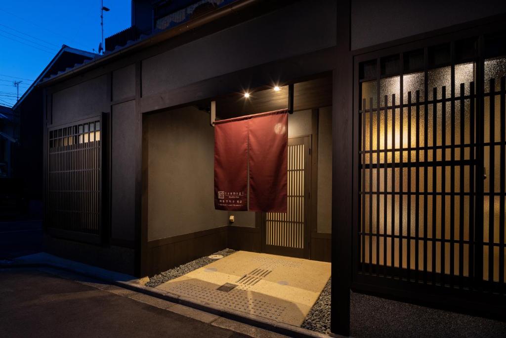 una puerta a un edificio con una bandera colgando de él en Tsumugi Shijomibudera Melody&Memory, en Kioto