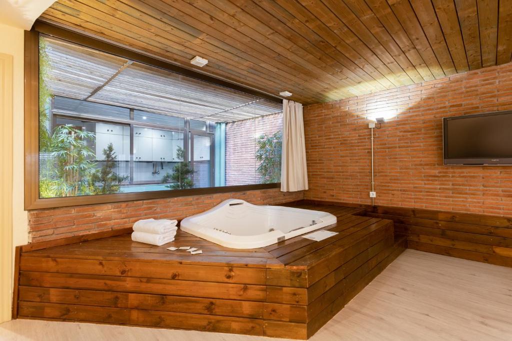  أبارتمنتوس دي في في برشلونة: حمام مع حوض استحمام وتلفزيون على جدار من الطوب