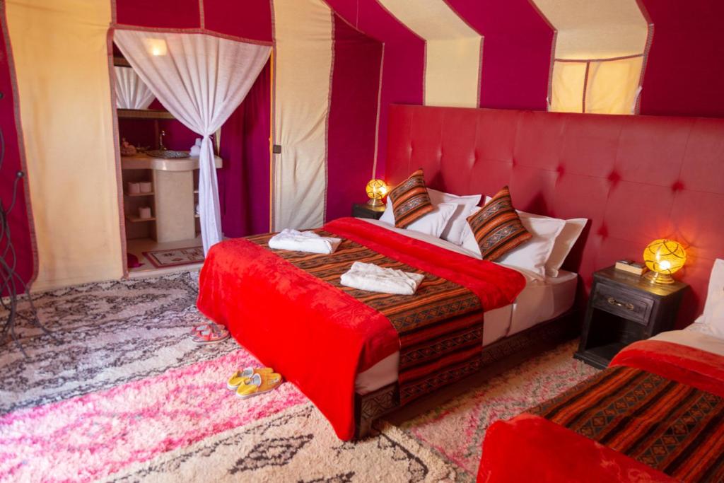a bedroom with a bed with a red head board at Sahara Desert Luxury Camp in Merzouga