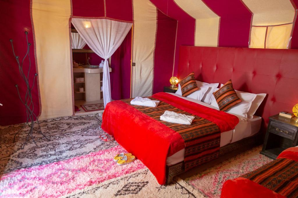 a bedroom with a bed with a red head board at Sahara Desert Luxury Camp in Merzouga