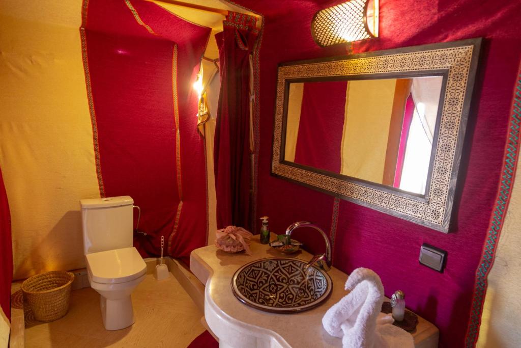 a bathroom with a sink and a toilet and a mirror at Sahara Desert Luxury Camp in Merzouga