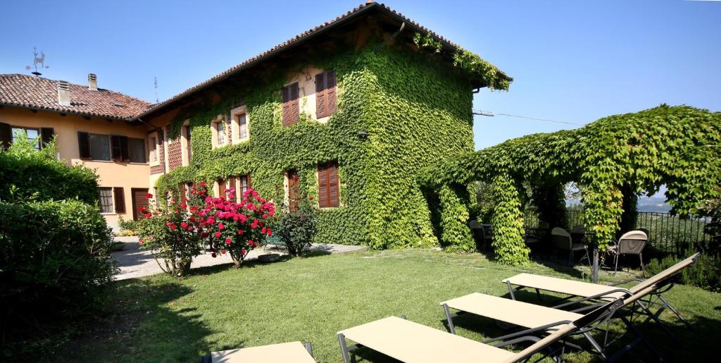 un edificio cubierto de hiedra verde con mesas y sillas en Cascina Delle Rose en Barbaresco