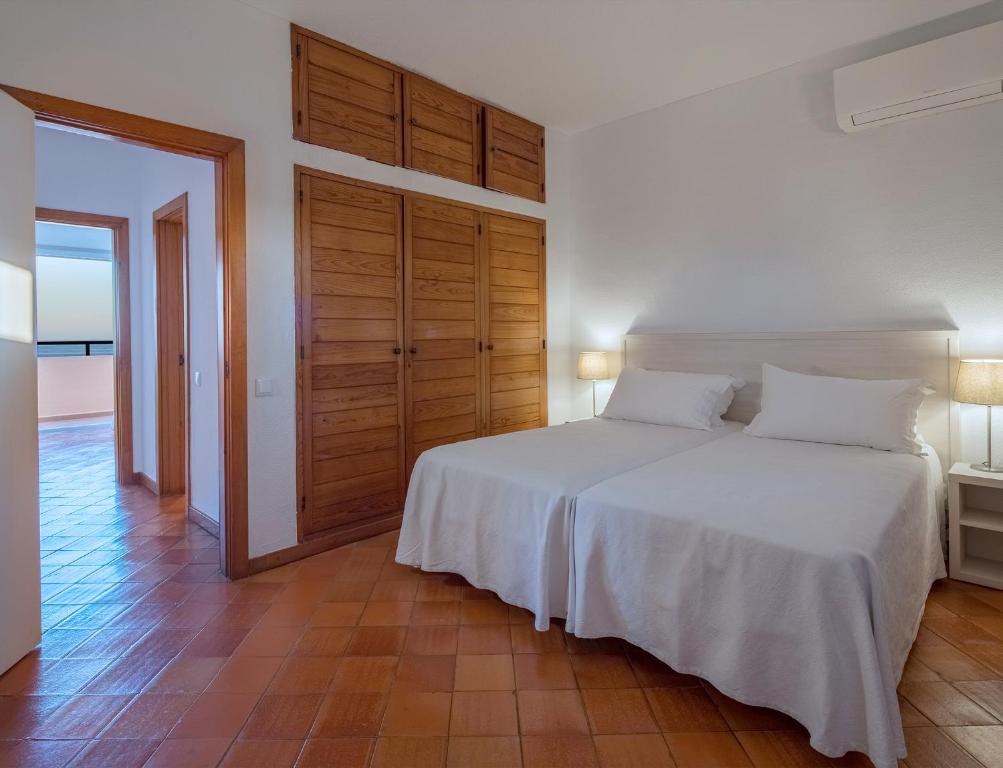 a bedroom with a white bed and a wooden door at Dom Pedro Lagos in Lagos