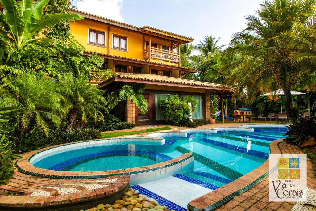 a house with a swimming pool in front of a house at Hotel Via dos Corais in Praia do Forte