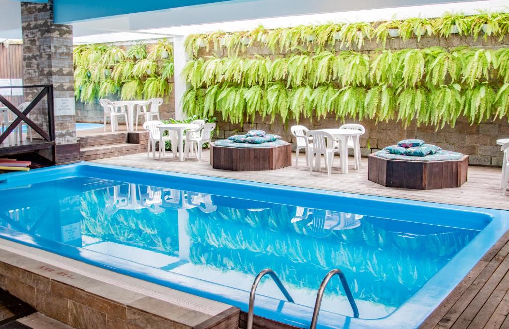 a swimming pool with chairs and a table at Hotel Rieger in Balneário Camboriú