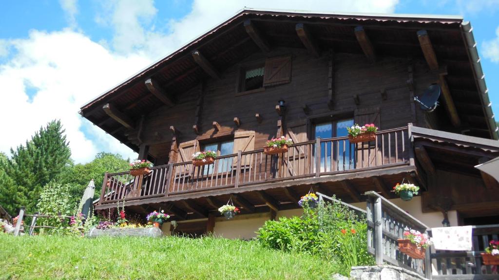 una casa de madera con flores en el balcón en Le nid d'aigle, en Arêches