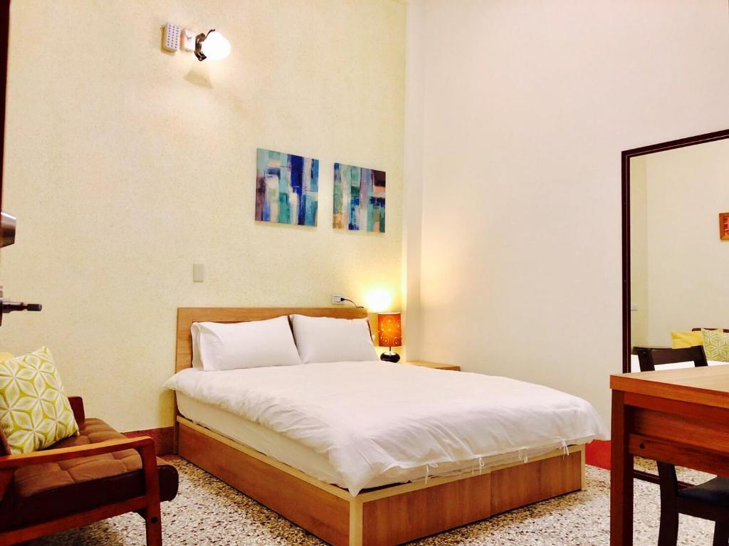 Schlafzimmer mit einem Bett, einem Schreibtisch und einem Spiegel in der Unterkunft Freedom B&B in Tainan