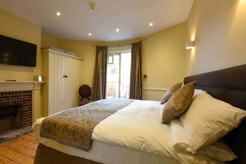 a bedroom with a large bed and a fireplace at Sutherland House in Southwold