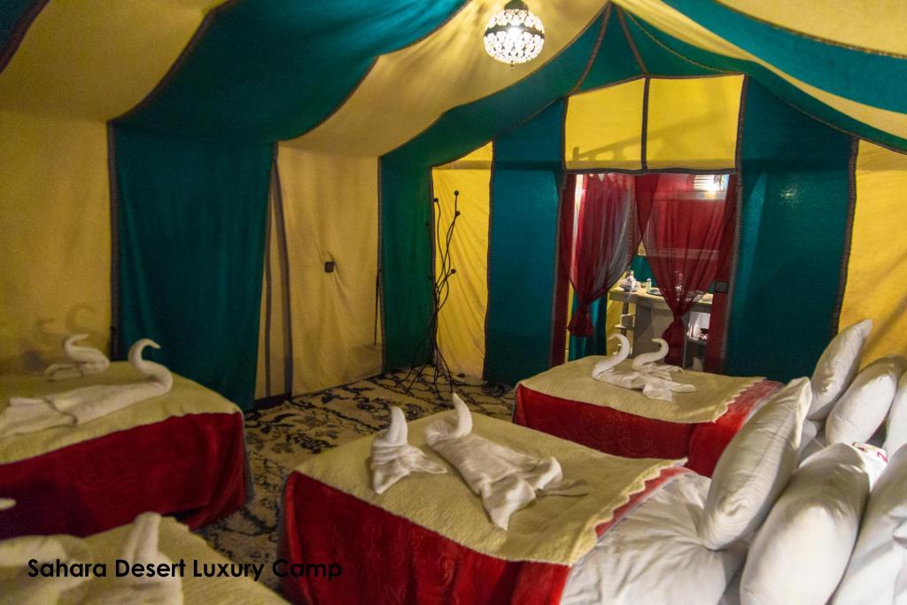 a tent with two beds in a room at Sahara Desert Luxury Camp in Merzouga