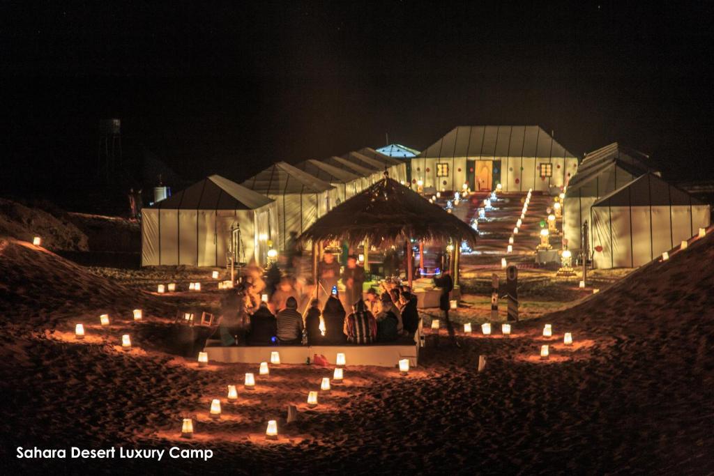 eine Gruppe von Menschen, die vor einem Gebäude mit Kerzen stehen in der Unterkunft Sahara Desert Luxury Camp in Merzouga