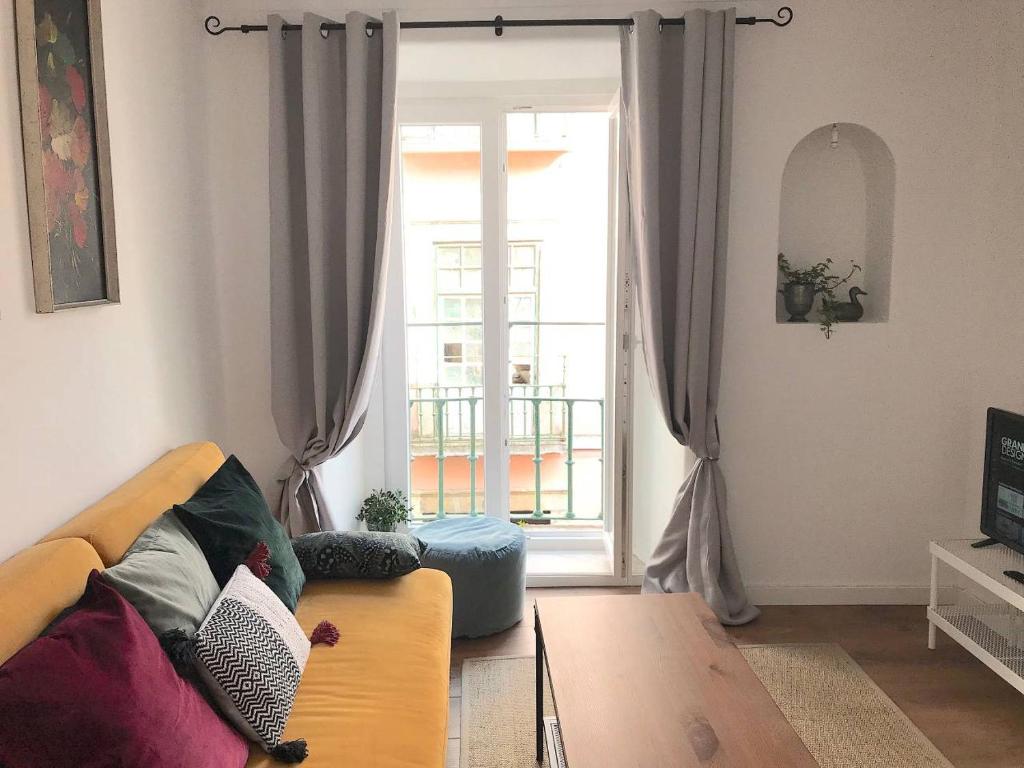 een woonkamer met een bank en een groot raam bij Gorgeous Bairro Alto in Lissabon