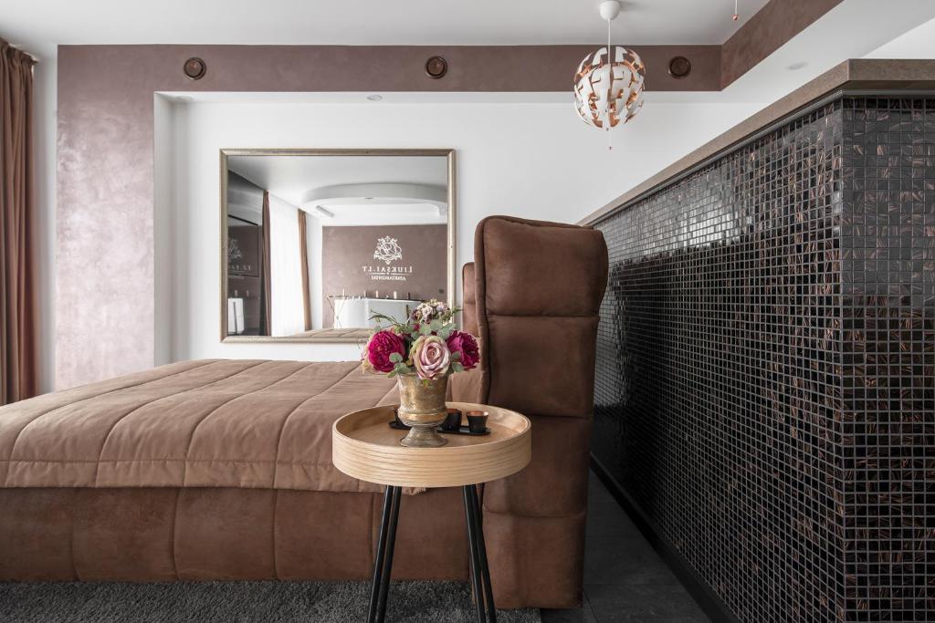 a bedroom with a bed and a table with flowers on it at Panorama-27 Jacuzzi Apartment in Klaipėda