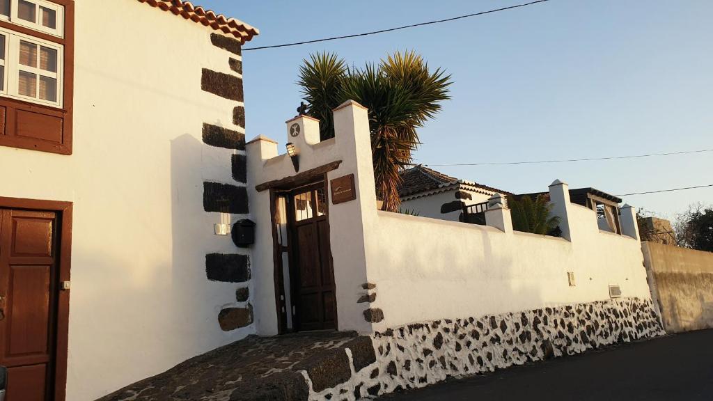un edificio bianco con una porta e una palma di Casitas La Montañita a El Paso
