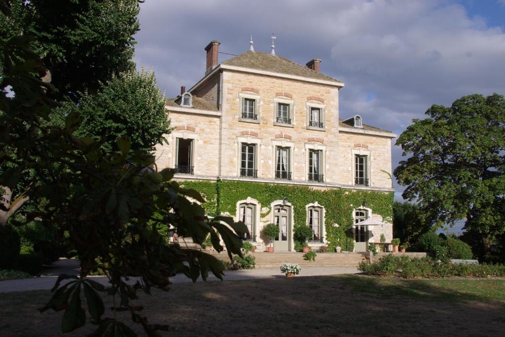 ein großes Backsteingebäude mit Efeu drauf in der Unterkunft Château des Charmes in Guéreins