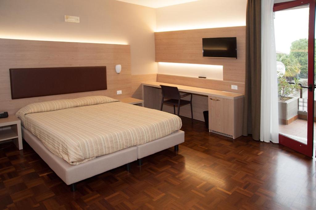 a bedroom with a bed and a desk and a television at HOTEL BUCA DI BACCO in Volta Mantovana