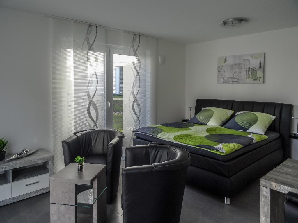a bedroom with a bed and two chairs and a table at Ferienapartment im Augustinus Park in Trier